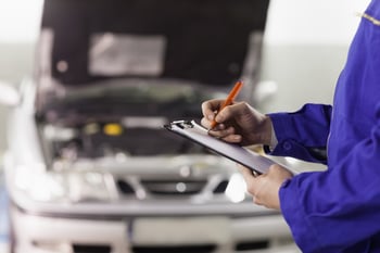 Closeup of a man writing on a clipboard in a garage.jpeg Closeup of a man writing on a clipboard in a garage.jpeg