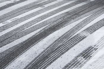 Multiple tracks of car tires, with a few footprints, in snow on pavement.jpeg